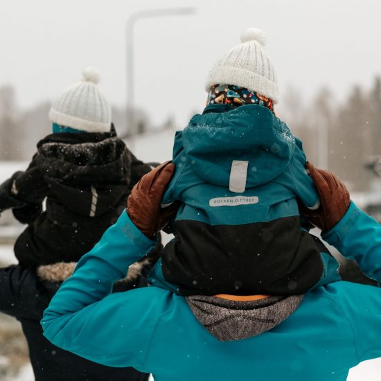 ulkoilua, äiti ja isä kävelevät lapset harteilla talvisessa maisemassa