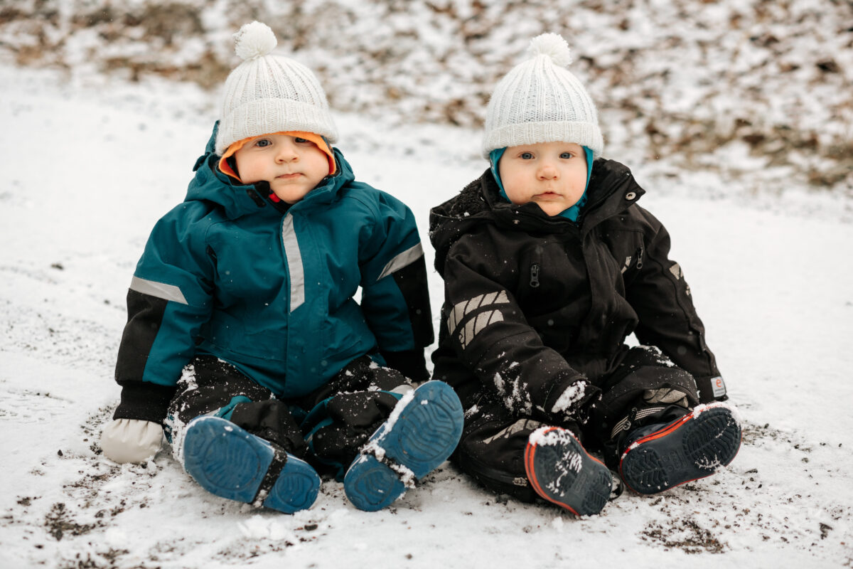 kaksoset, taaperot, istuvat talvihaalareissa lumessa