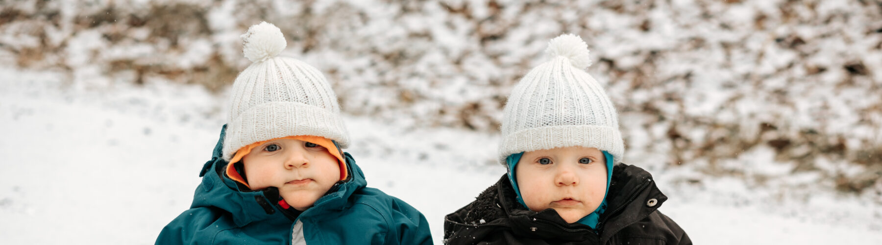 kaksoset, taaperot, istuvat talvihaalareissa lumessa