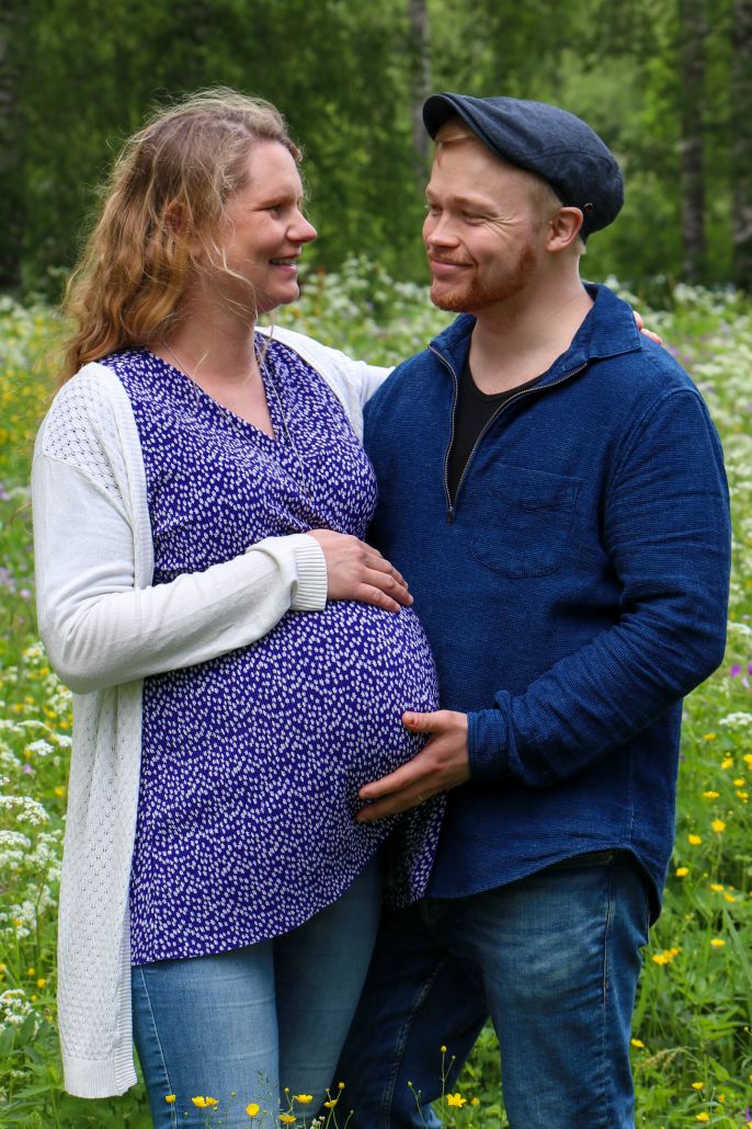 kaksosia odottava pariskunta, nainen ja mies, kädet raskausvatsalla