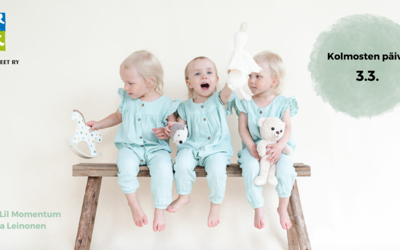Kolmosten päivä 3.3. Kolme leikki-ikäistä vaaleatukkaista lasta istuu vanhalla puupenkillä rinnakkain pehmolelujen kanssa.