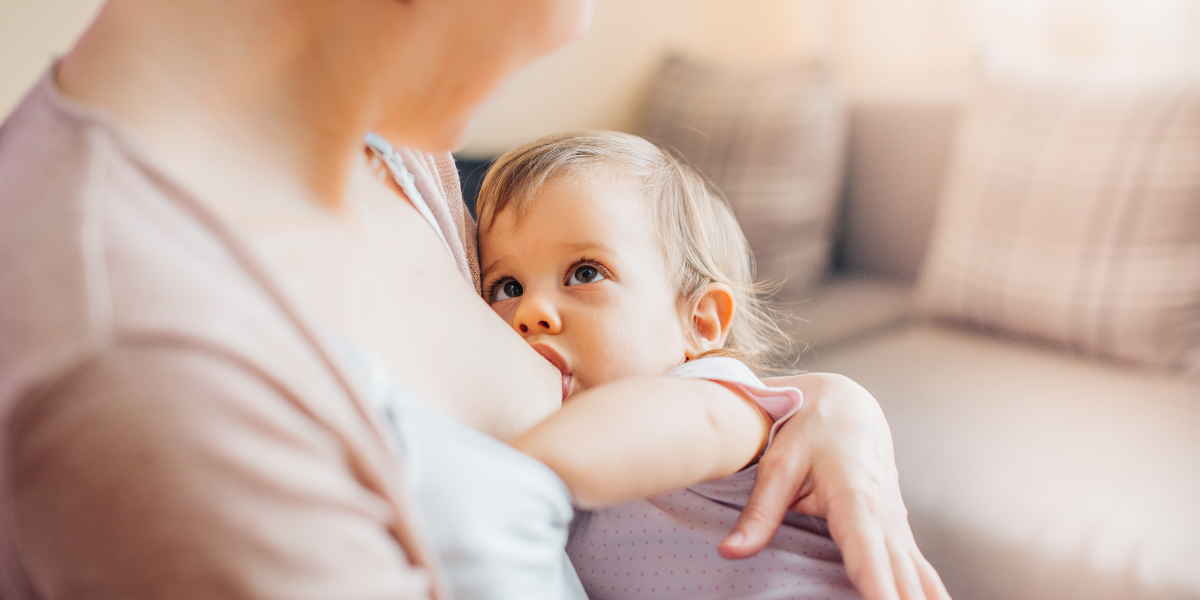 Äiti imettää sylissään taaperoikäistä lasta, joka katsoo äitiä silmiin.